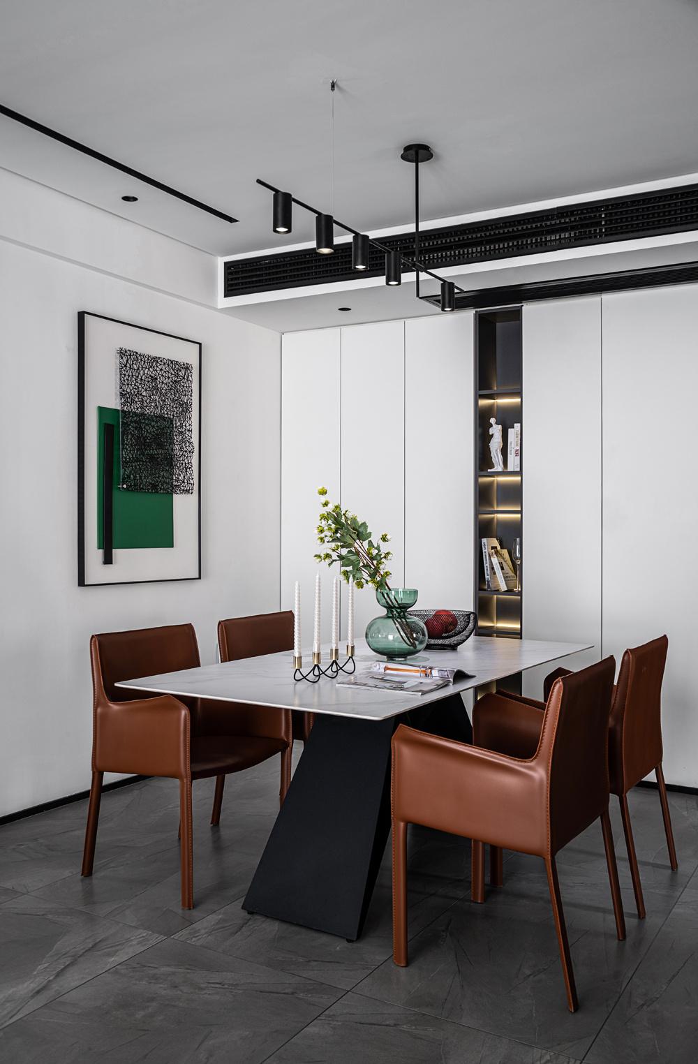 餐厅一侧的做出开放格与哑光白门板，将空间的收纳功能发挥到极致，在不同材质与不同色调的切换中，将业主的爱好与生活合理的安置，咖啡色的餐椅与白色柜体碰撞，摆脱灰色空间的沉闷之感。